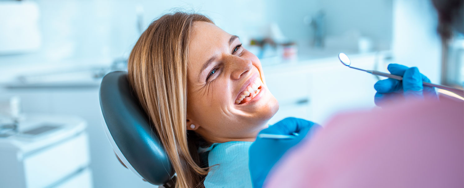 Patientin auf Zahnarztstuhl lächelt Behandler:in an